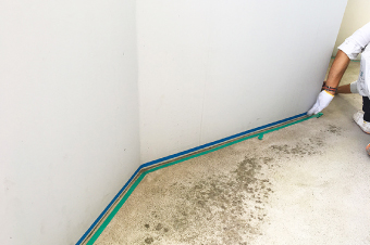 通路部分の防水工事にて床と壁の取り合い部分にマスキングテープで施工箇所を区切っていきます